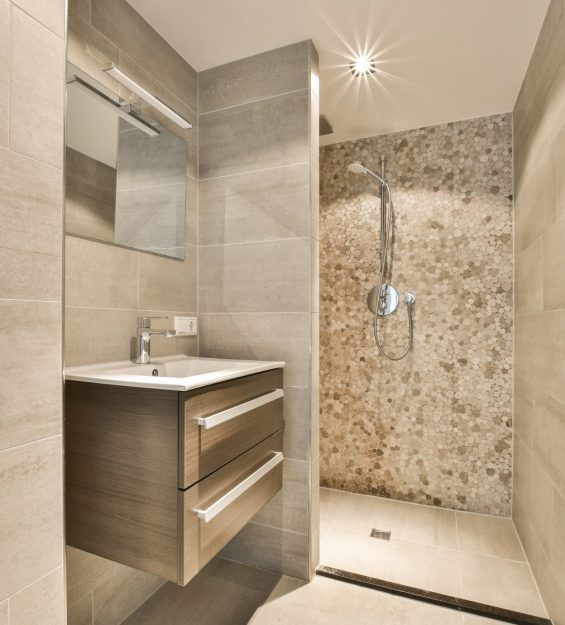 a modern bathroom with marble walls and tile flooring, there is a large mirror on the wall above the sink